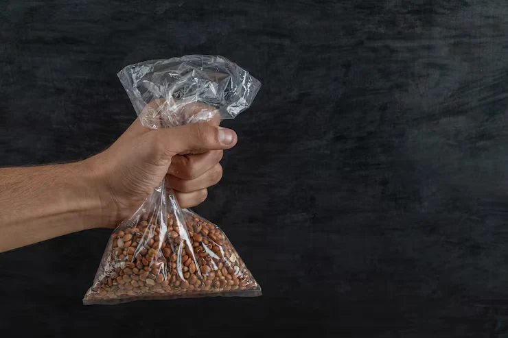 A hand holding a clear bag of dried kidney beans