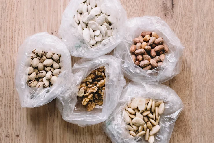 Five kinds of nuts in open clear bags on a wooden table