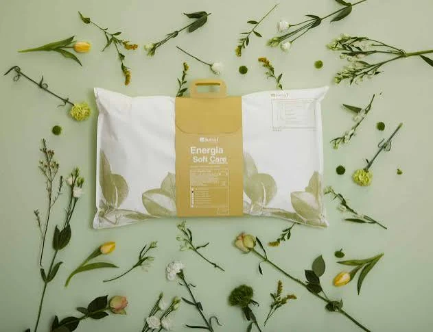 White pillow with a yellow printed band and carry handle, arranged with flowers
