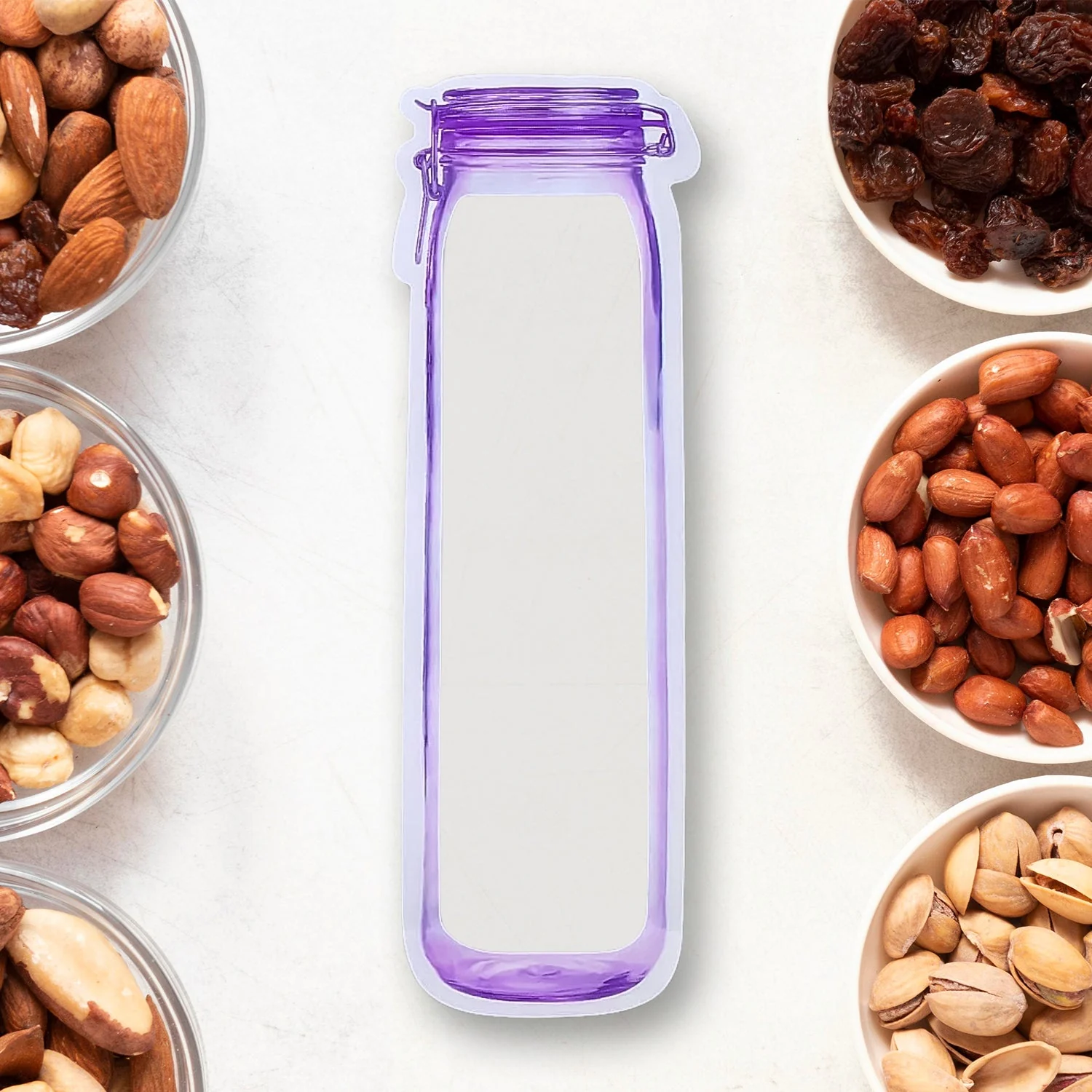 Transparent bottle-shaped zipper pouch with a purple printed outline beside bowls of nuts
