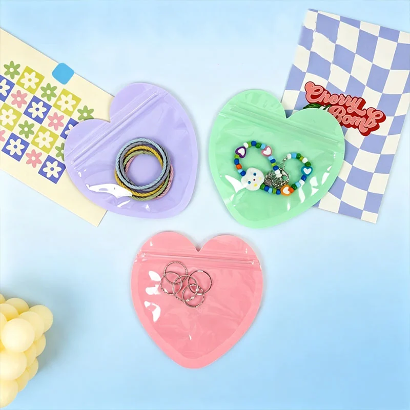 Pink, green and purple heart-shaped zipper pouches holding small accessories