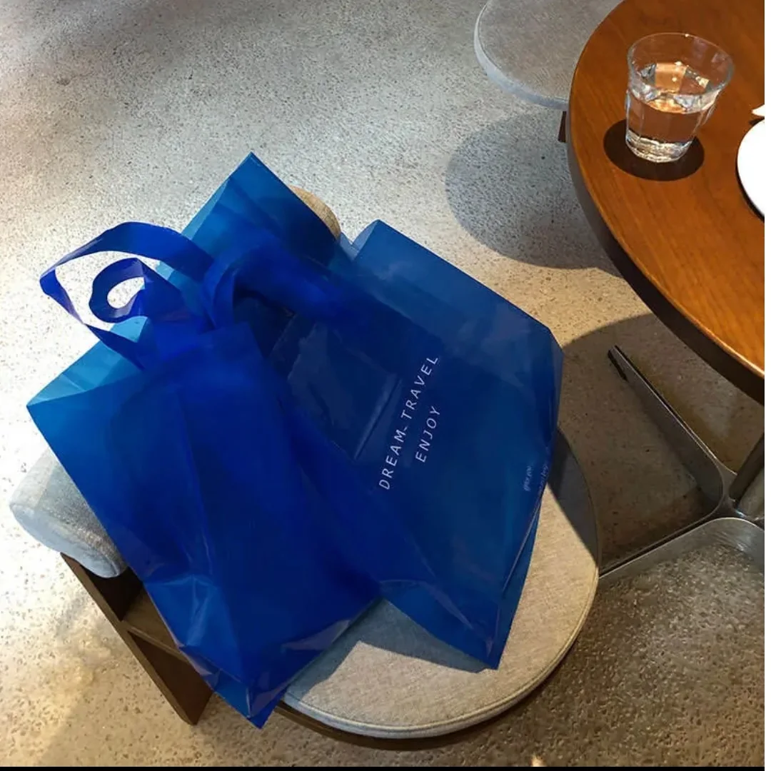 Blue printed shopping bags displayed on an upholstered stool