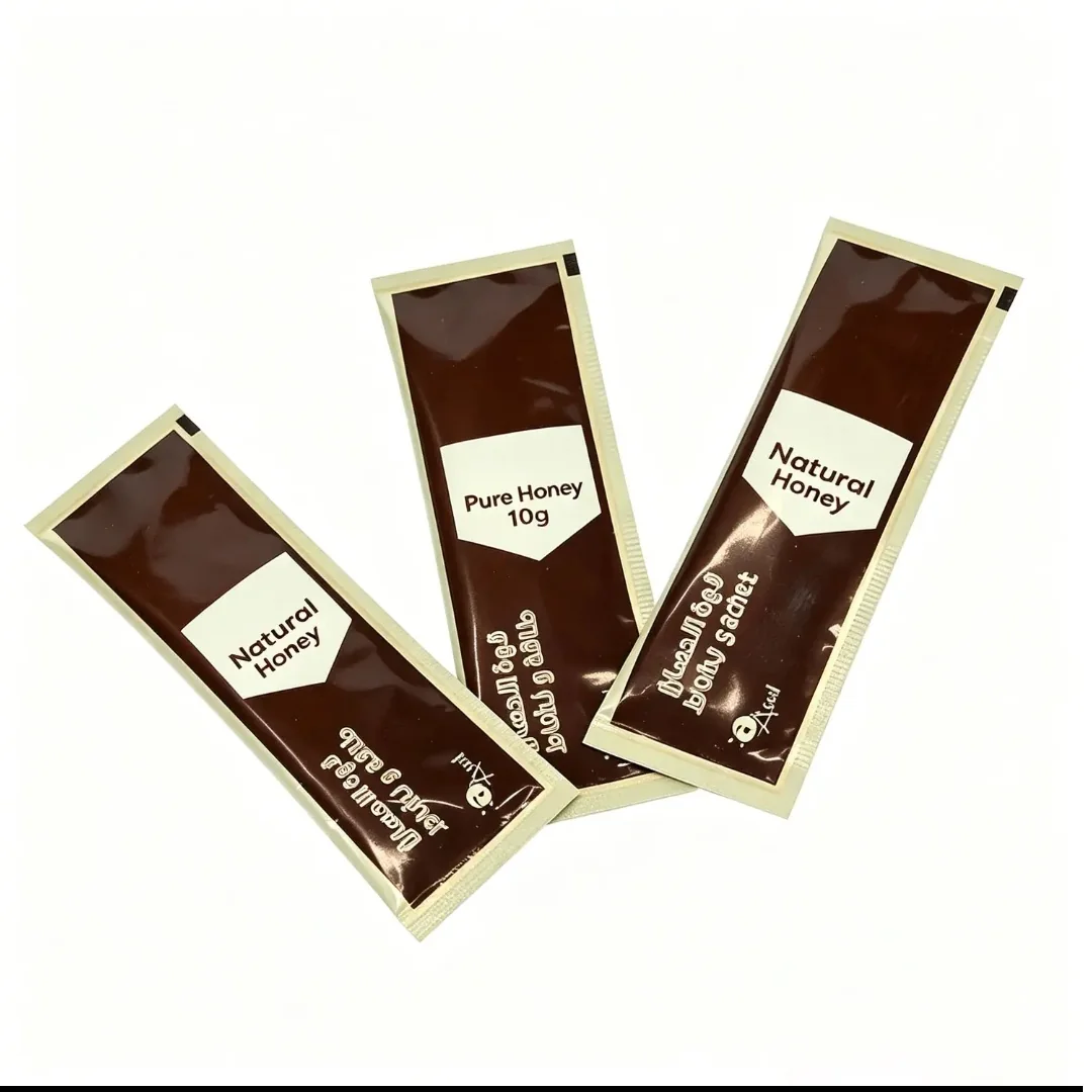 Three brown printed honey stick sachets on a white background