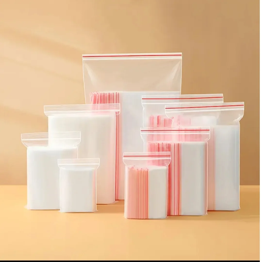 Assorted clear zip bags with red closure lines on a peach background