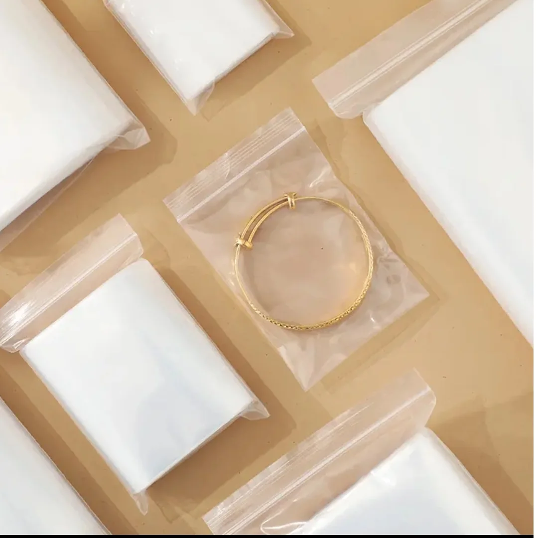 Clear zip pouches arranged beside gold-coloured jewellery and display cushions