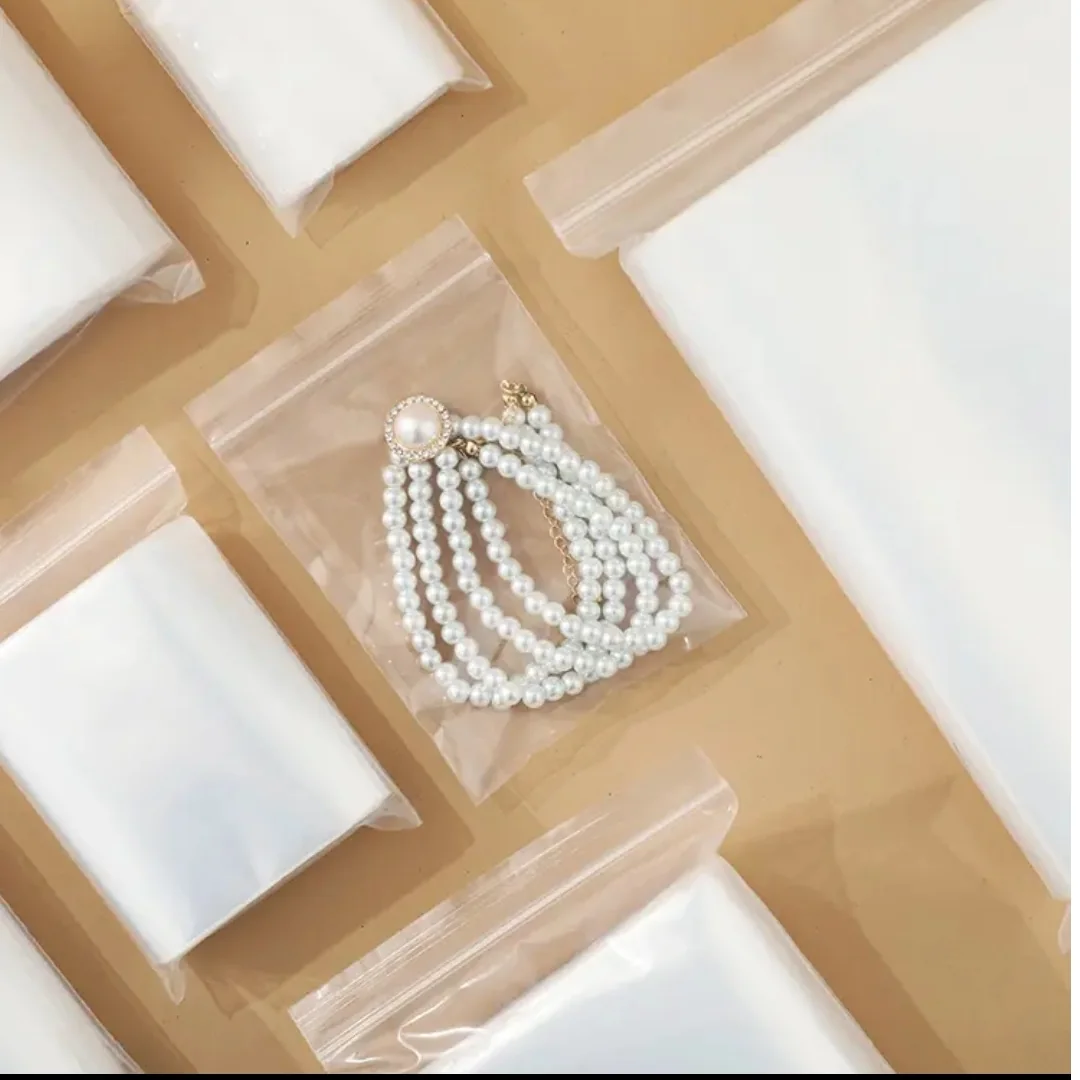 Clear zip pouches arranged beside pearl jewellery and white display cushions