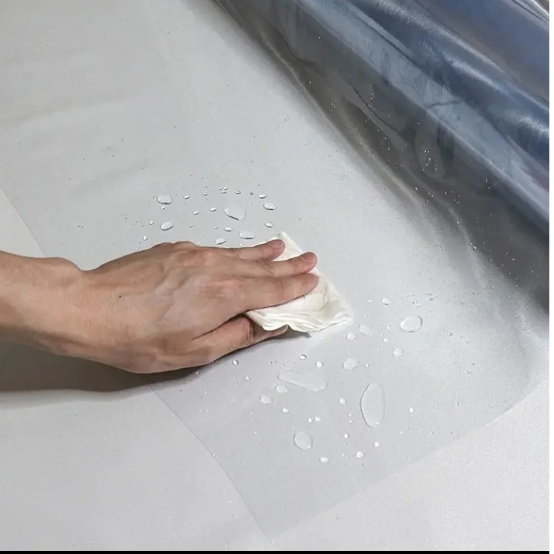 Hand wiping a surface beside a sheet of protective film